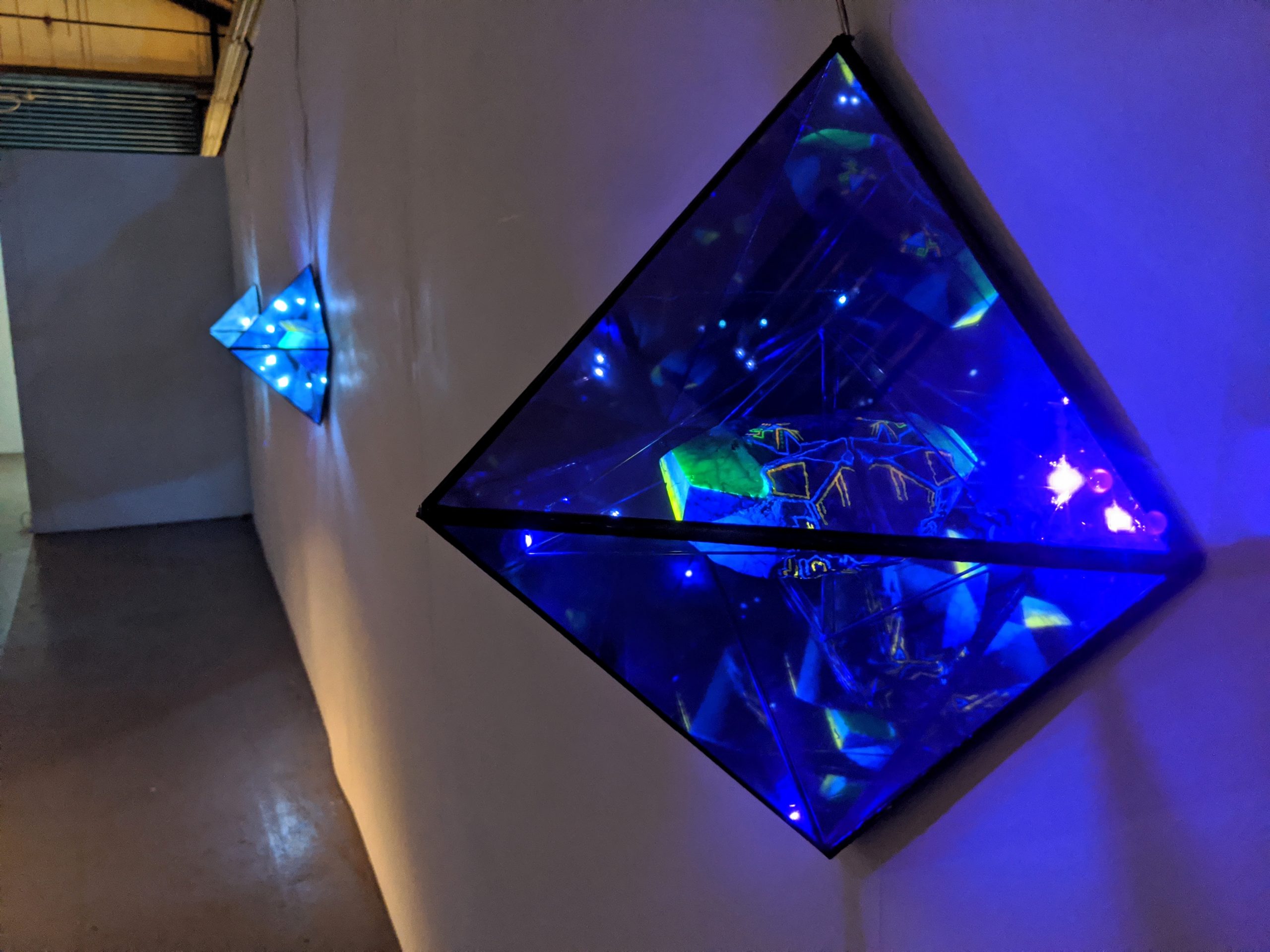 glass pyramid sculpture on wall with blue LED lights