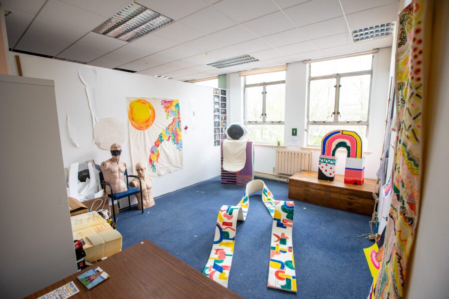 Colourful pieces of artwork in a studio with large windows. The artworks are shapes on the floor using lots of colour.